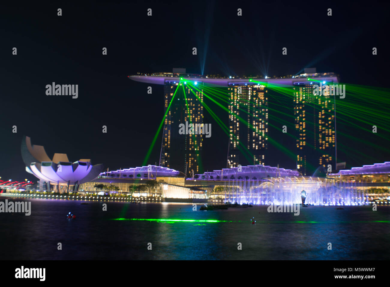 The famous Marina Bay Sands hotel during its light show with its reflecting on the Singapore river in the marina in Singapore at night. Stock Photo