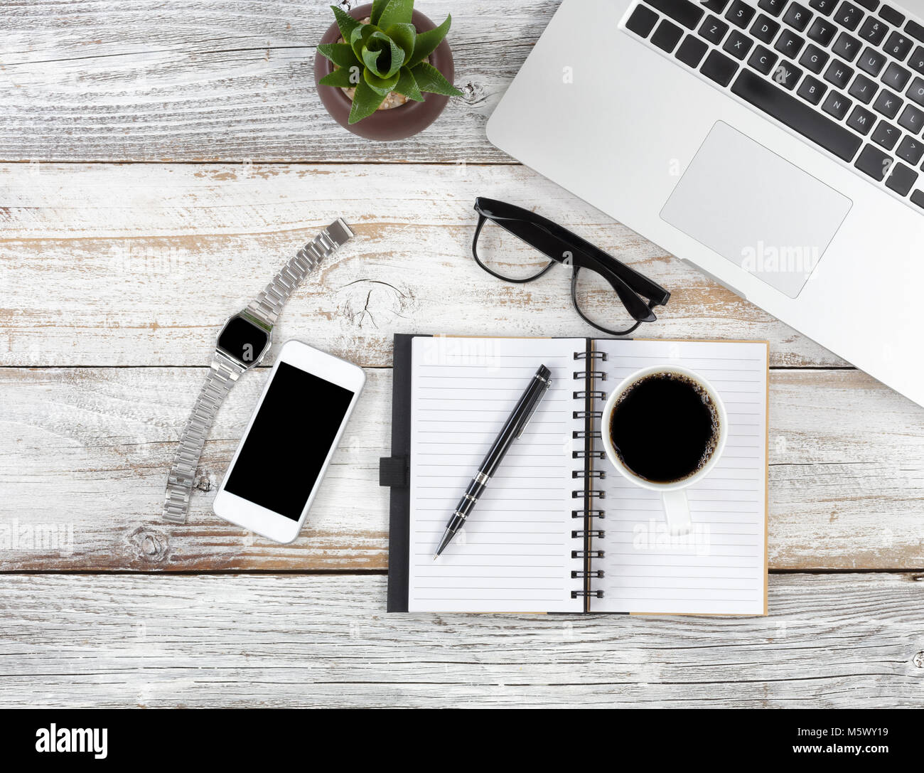 Office desktop with laptop, calendar, coffee and writing materials on