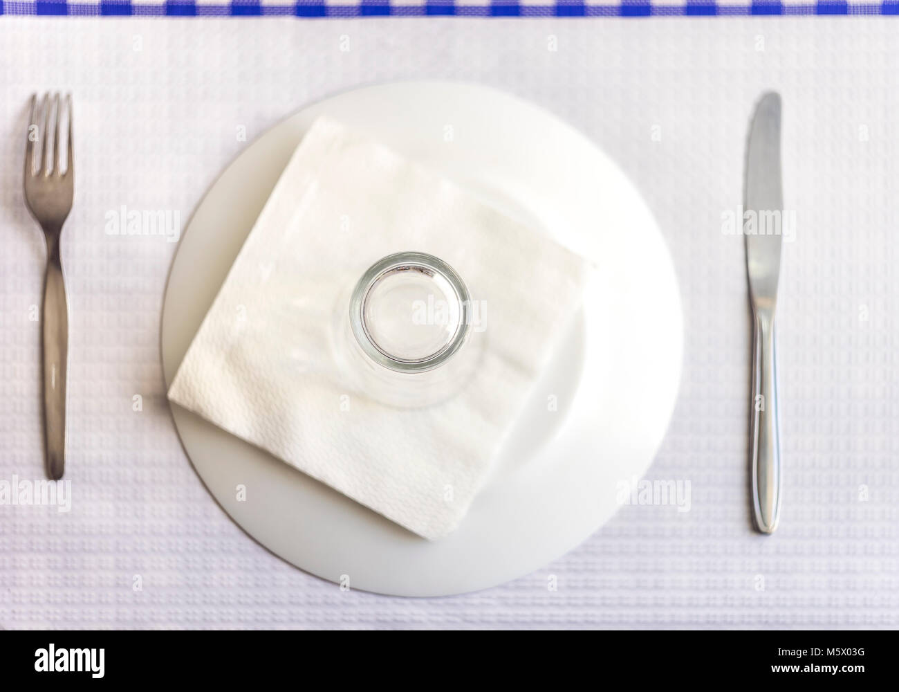 Single tableware - plate, fork, knife, water glass and napkin in the restaurant Stock Photo