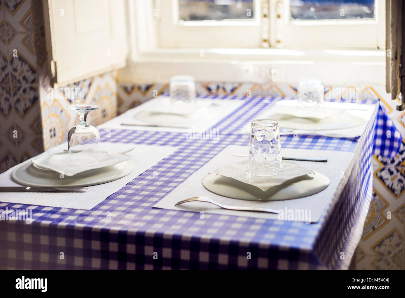 Table in Portuguese restaurant with traditional tiles ready for four people Stock Photo