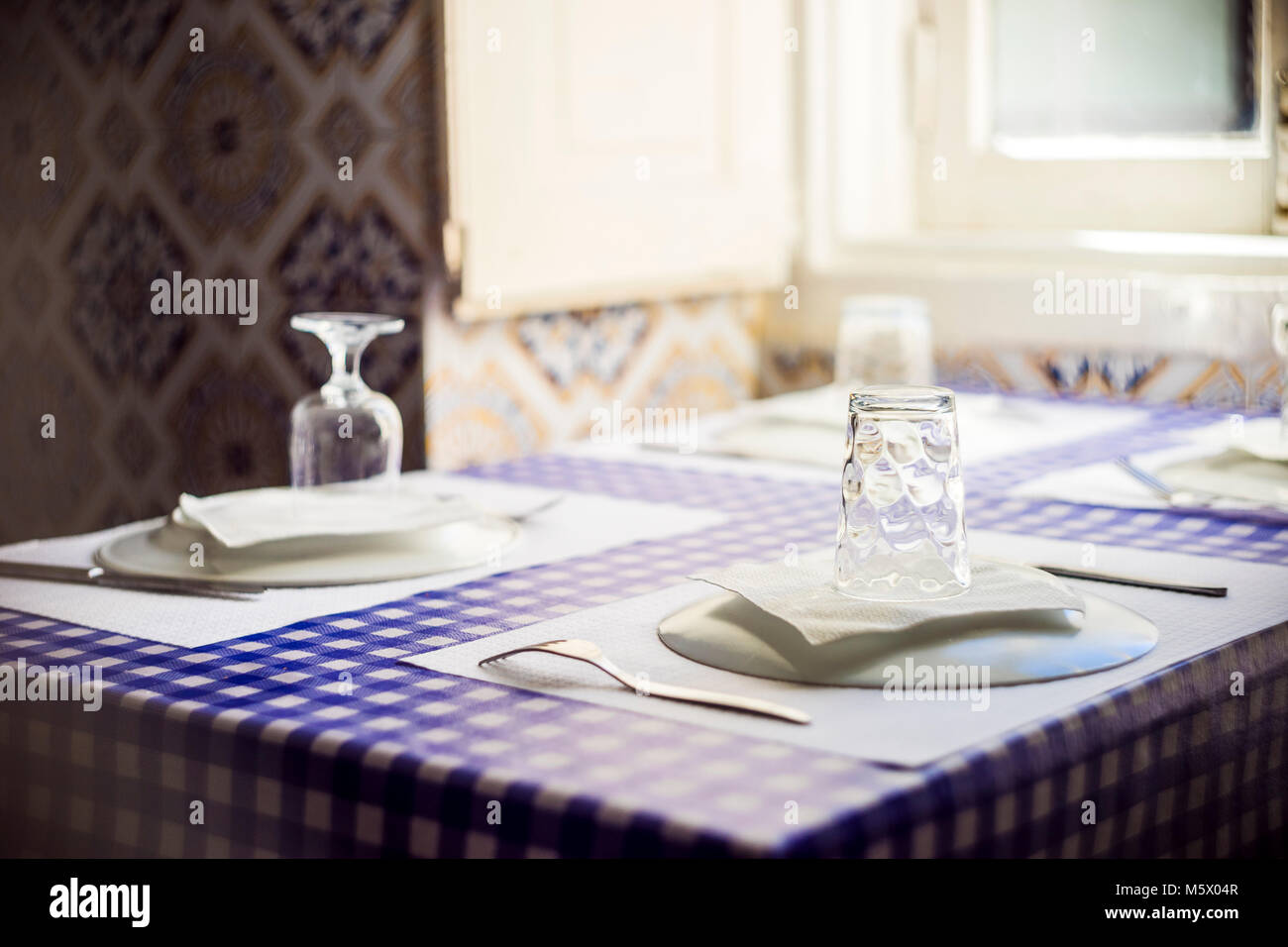 Table in Portuguese restaurant with traditional tiles ready for four people Stock Photo