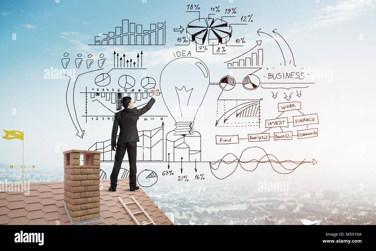 Rear view of businessman on house roof drawing his new business ...