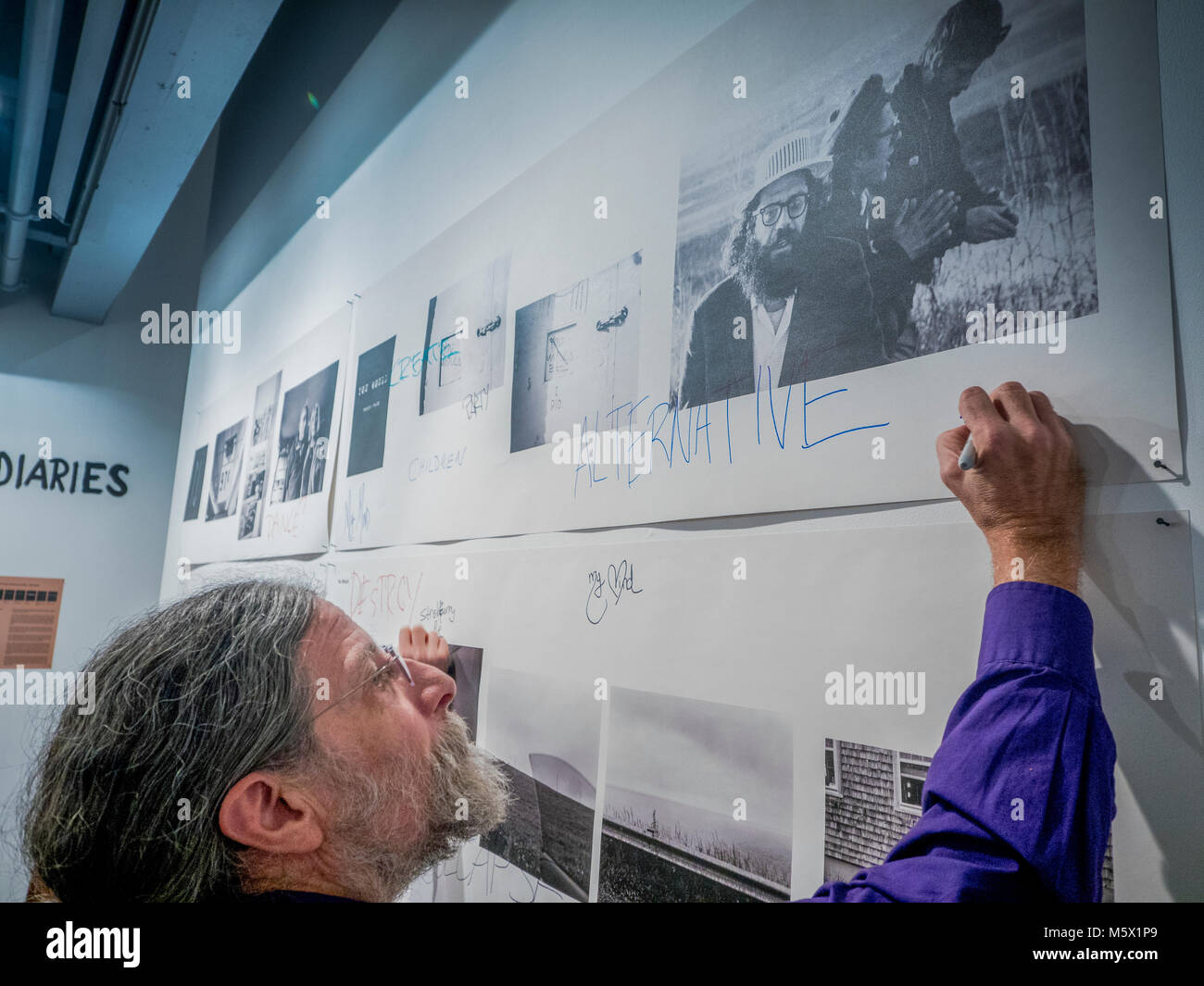 Portland, Oregon, USA. 26 FEB, 2018. Blue Sky Gallery co-founder Christopher Rauschenberg, son of the American painter Robert Rauschenberg, defaces a Robert Frank image of the poet Alan Ginsberg  at Blue Sky Gallery in Portland, Oregon, USA. The work was destroyed in a “Destruction Dance” performance defacing the photographs with ink and mutilation with scissors, knives and even ice skates  at the end of it’s run. The destruction was Frank's protest regarding today's greed in the global art market. Credit: Ken Hawkins/Alamy Live News Stock Photo