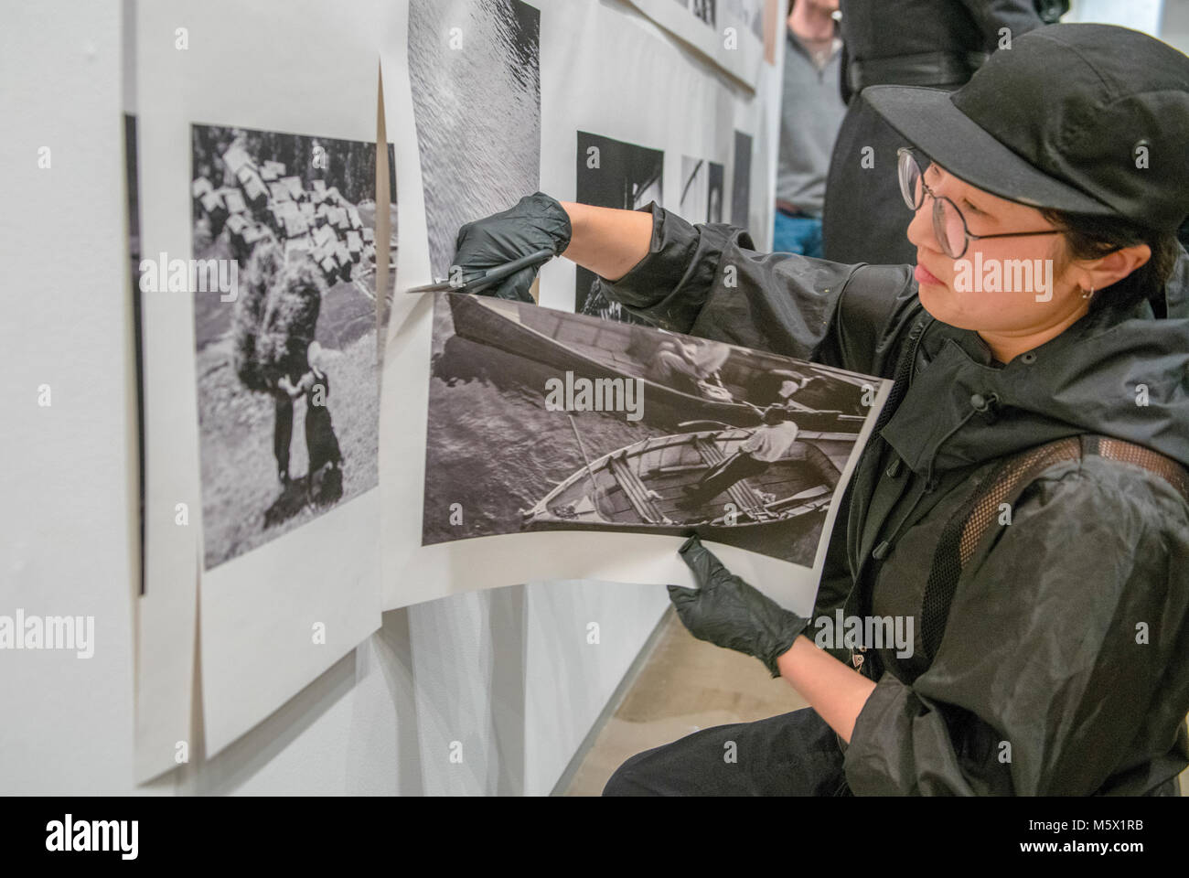 Portland, Oregon, USA. 26 FEB, 2018. A performance artist cuts the work of the photographer Robert Frank from the wall at Blue Sky Gallery in Portland, Oregon, USA. The work was destroyed in a “Destruction Dance” performance defacing the photographs with ink and mutilation with scissors, knives and even ice skates  at the end of it’s run. The destruction was Frank's protest regarding today's greed in the global art market. Credit: Ken Hawkins/Alamy Live News Stock Photo