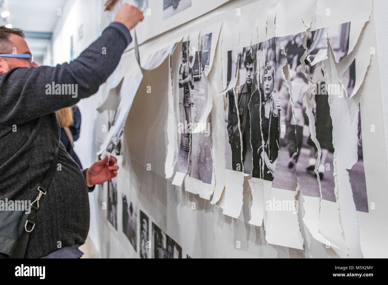 Portland, Oregon, USA. 26 FEB, 2018. The photographer Robert Frank's work from his ground breaking book "The Americans" hangs  defaced as a gallery goer shreds it at Blue Sky Gallery in Portland, Oregon, USA. The work was destroyed in a “Destruction Dance” performance defacing the photographs with ink and mutilation with scissors, knives and even ice skates  at the end of it’s run. The destruction was Frank's protest regarding today's greed in the global art market. Credit: Ken Hawkins/Alamy Live News Stock Photo