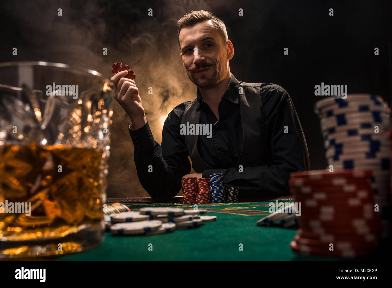 Man is playing poker with a cigar and a whiskey. A man winning all the