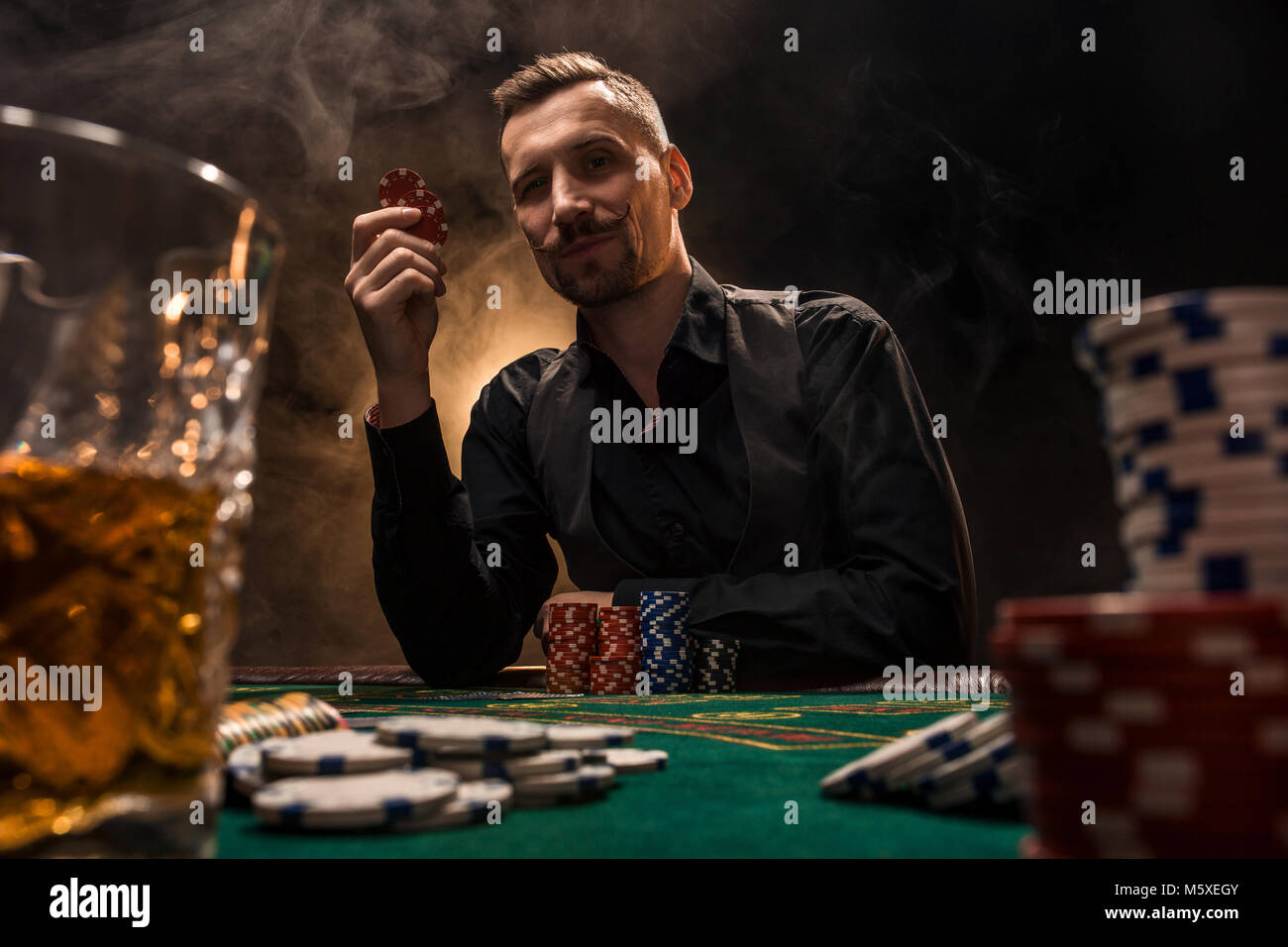 Man is playing poker with a cigar and a whiskey. A man winning all the