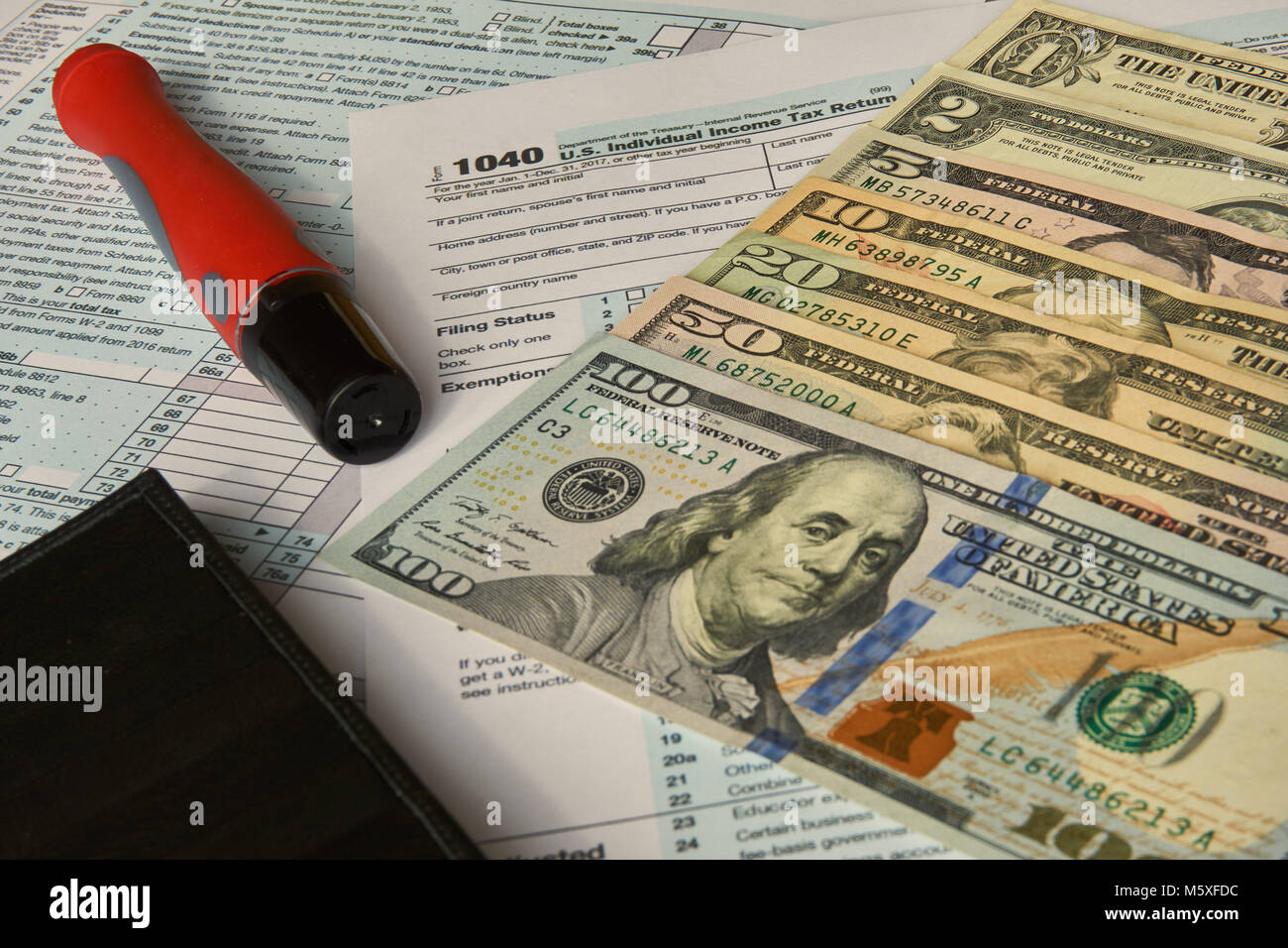 US 1040 Tax Form next to USD Dollars, Pen and Wallet Stock Photo