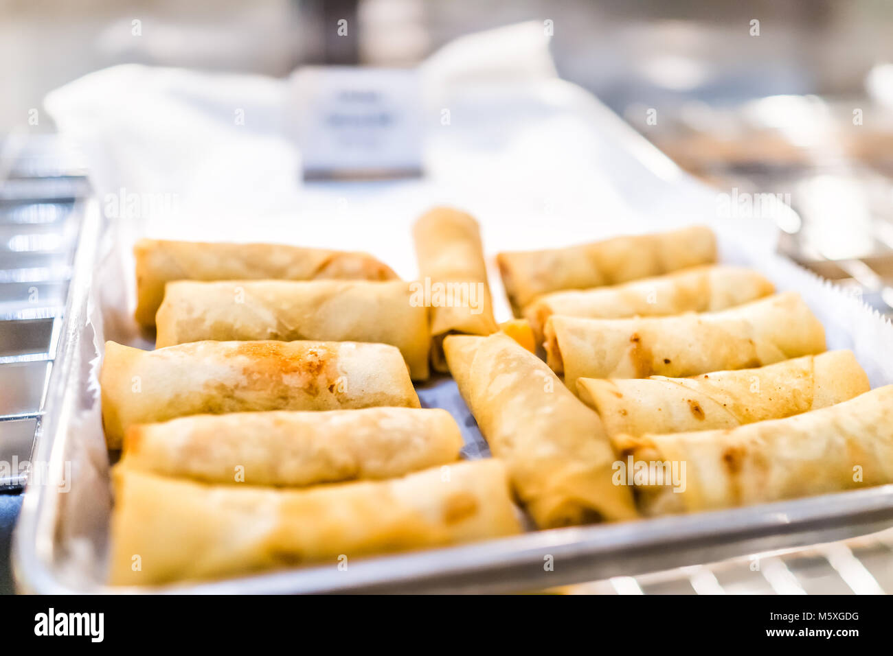 Closeup of fried greasy spring rolls on tray display in restaurant