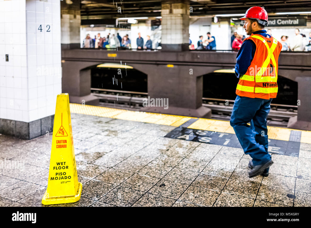 New York City, USA - October 29, 2017: Employee worker inspecting leak in underground transit empty large platform in NYC Subway Station, wet floor si Stock Photo