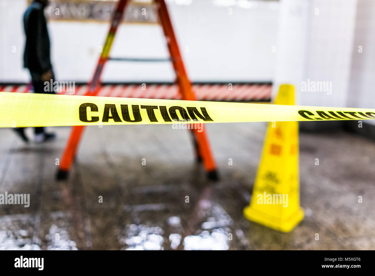 Caution tape sign in underground transit empty large platform in New York City NYC Subway Station in Grand Central, ladder, wet floor cone Stock Photo