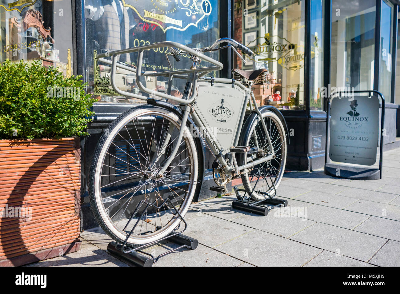 White vintage bike used as a shop display outside the Equinox barbers shop in Oxford Street, Southampton, England, UK Stock Photo