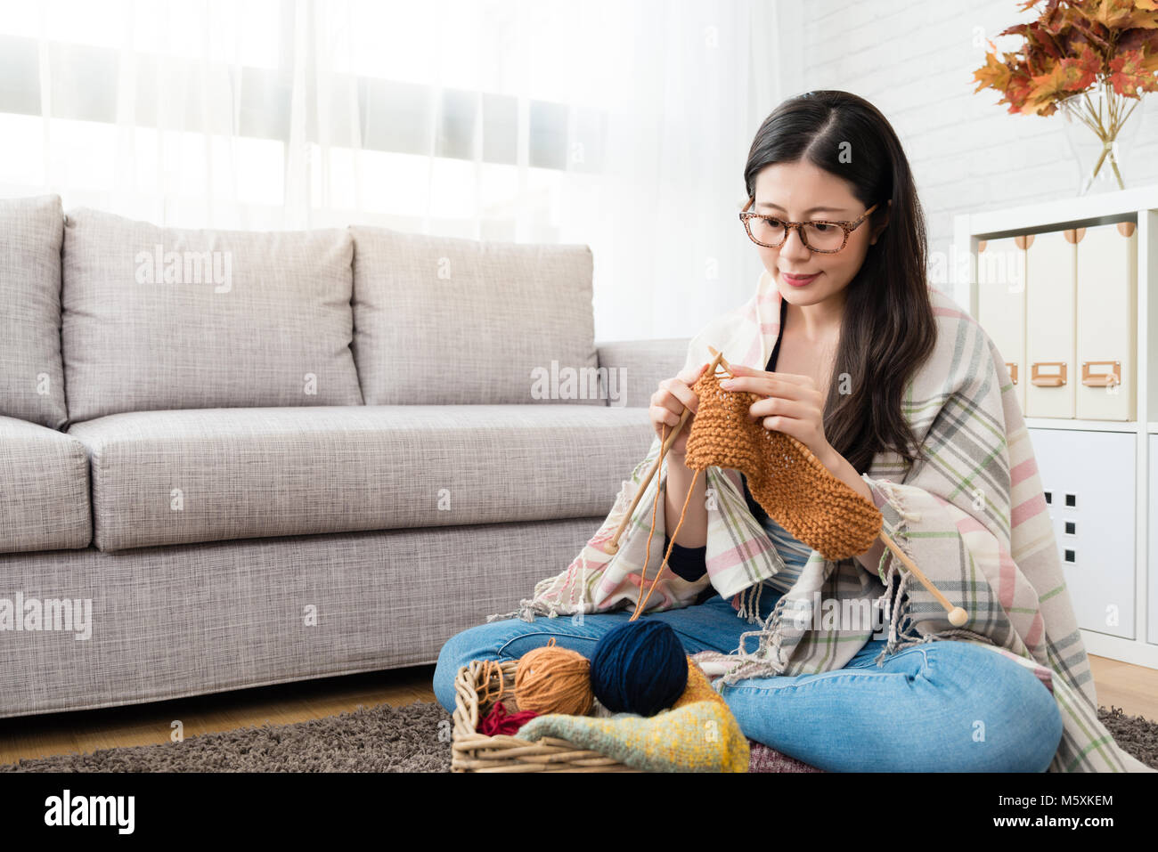 beautiful Asian women sitting on the floor of the living room and knitting for winter Christmas at home Stock Photo
