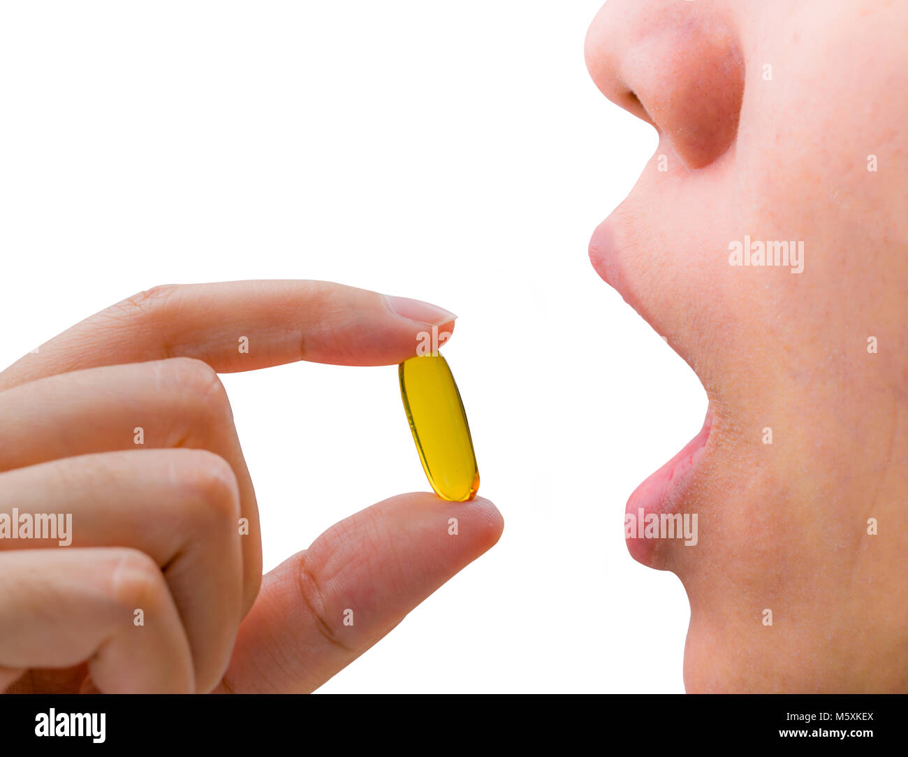 Young woman hand hold fish oil capsule near open mouth. Woman taking