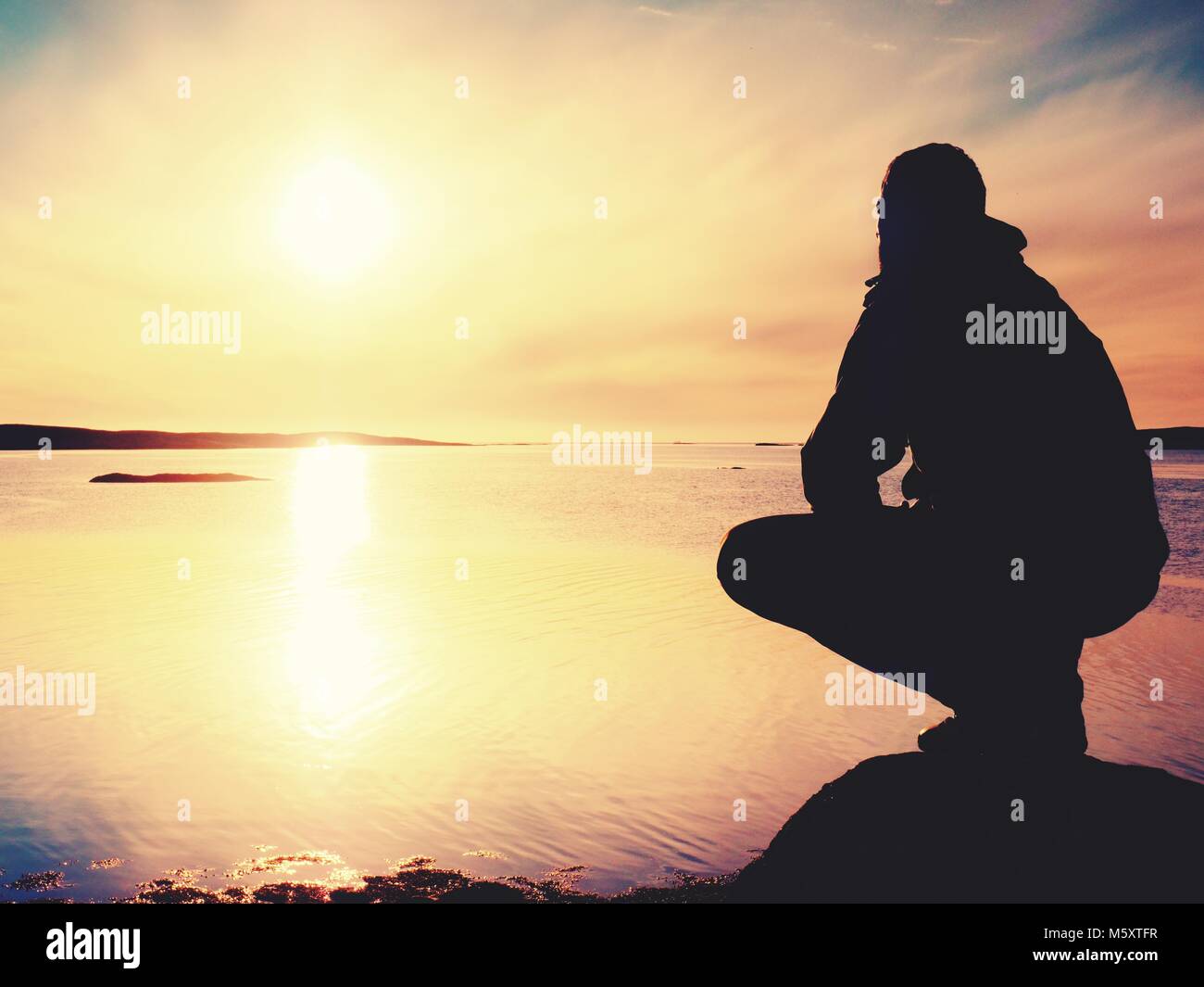 Lonely Man Hiker Sits Alone On The Rocky Coast And Enjoying Sunset Stock Photo Alamy