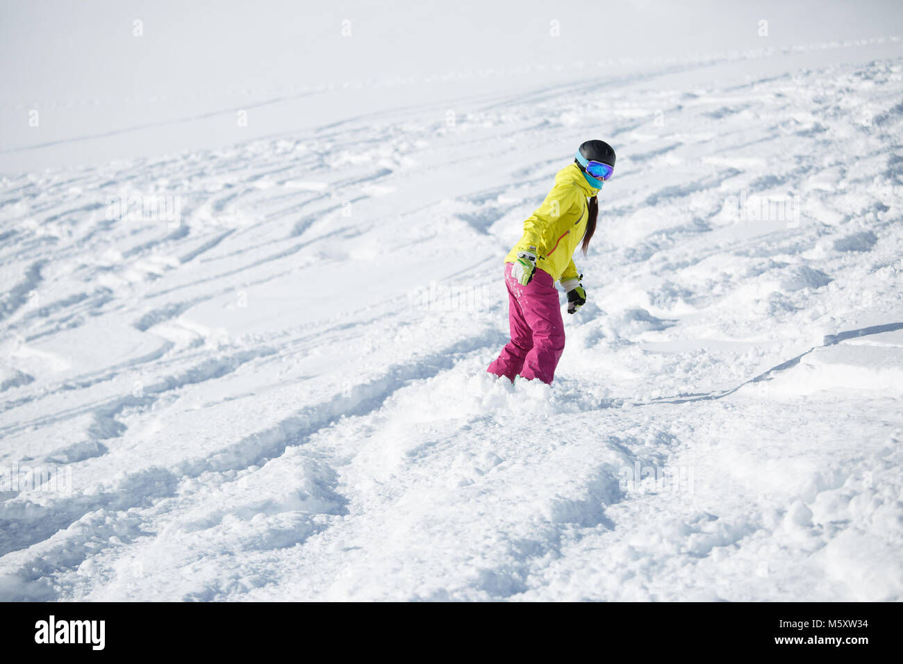 Picture of athlete girl in helmet and mask, snowboarding from snowy