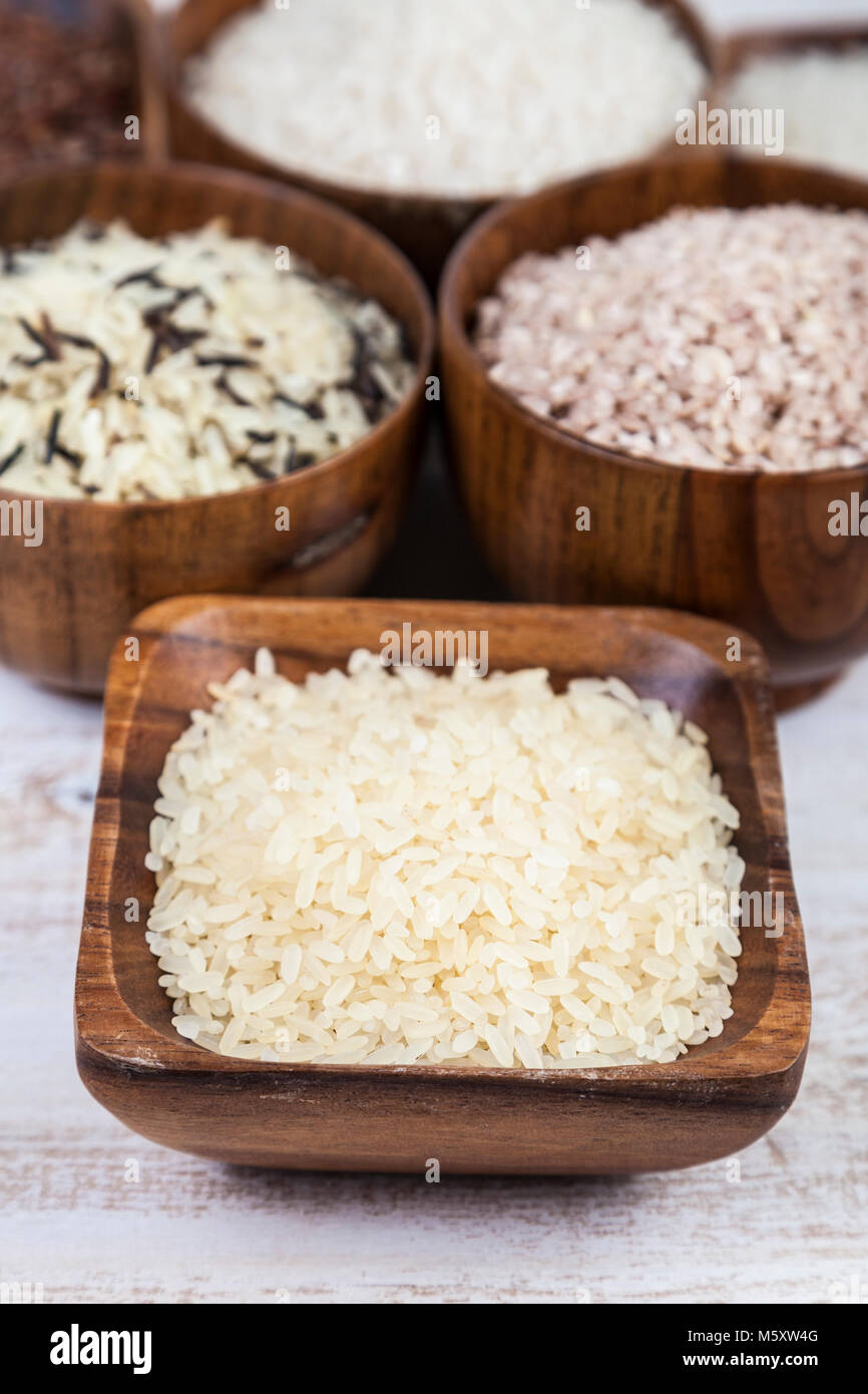 Six bowls with different varieties of rice on a wooden background ...