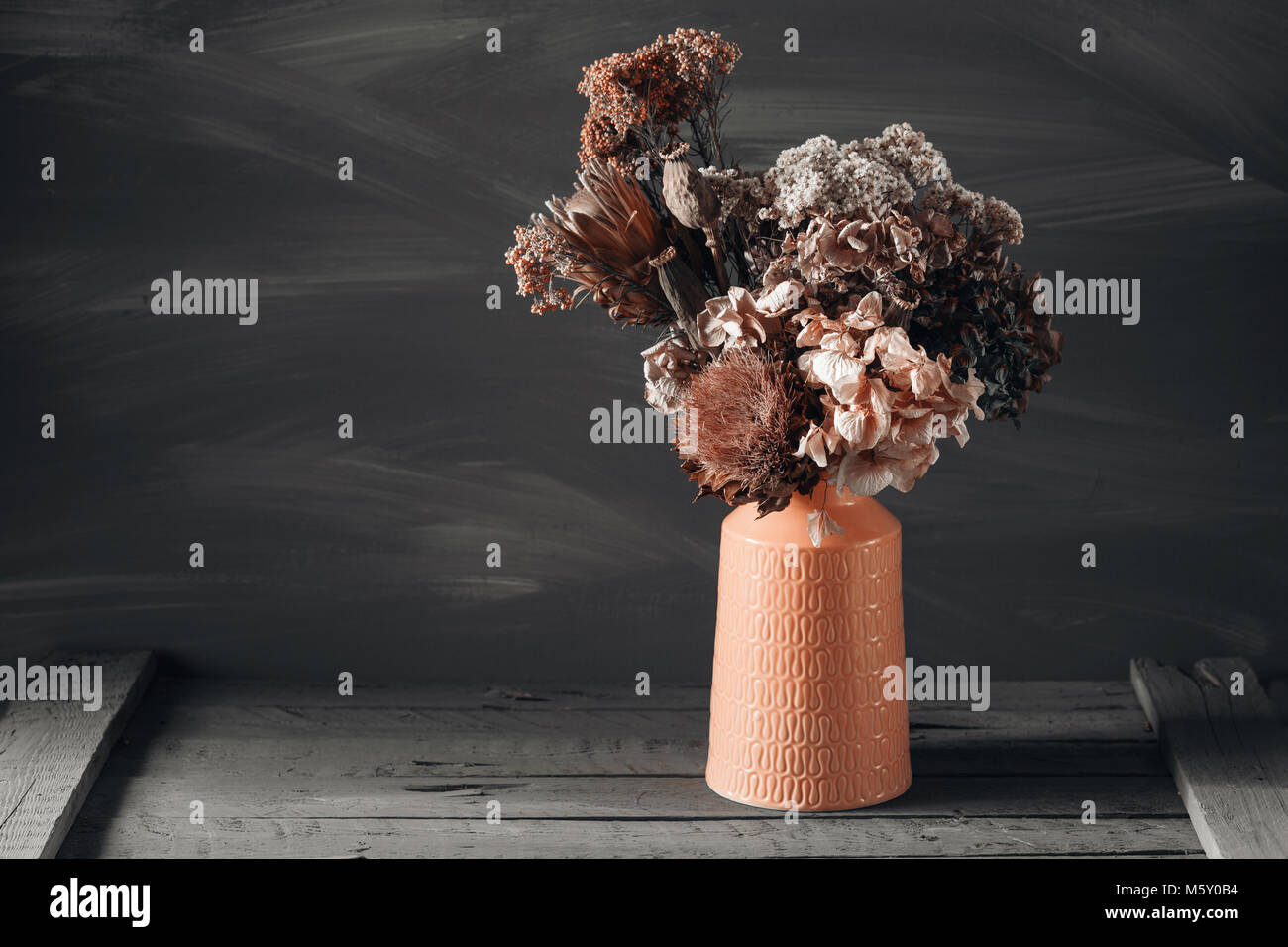 Still life image of dried flowers in rustic vase against weathered ...