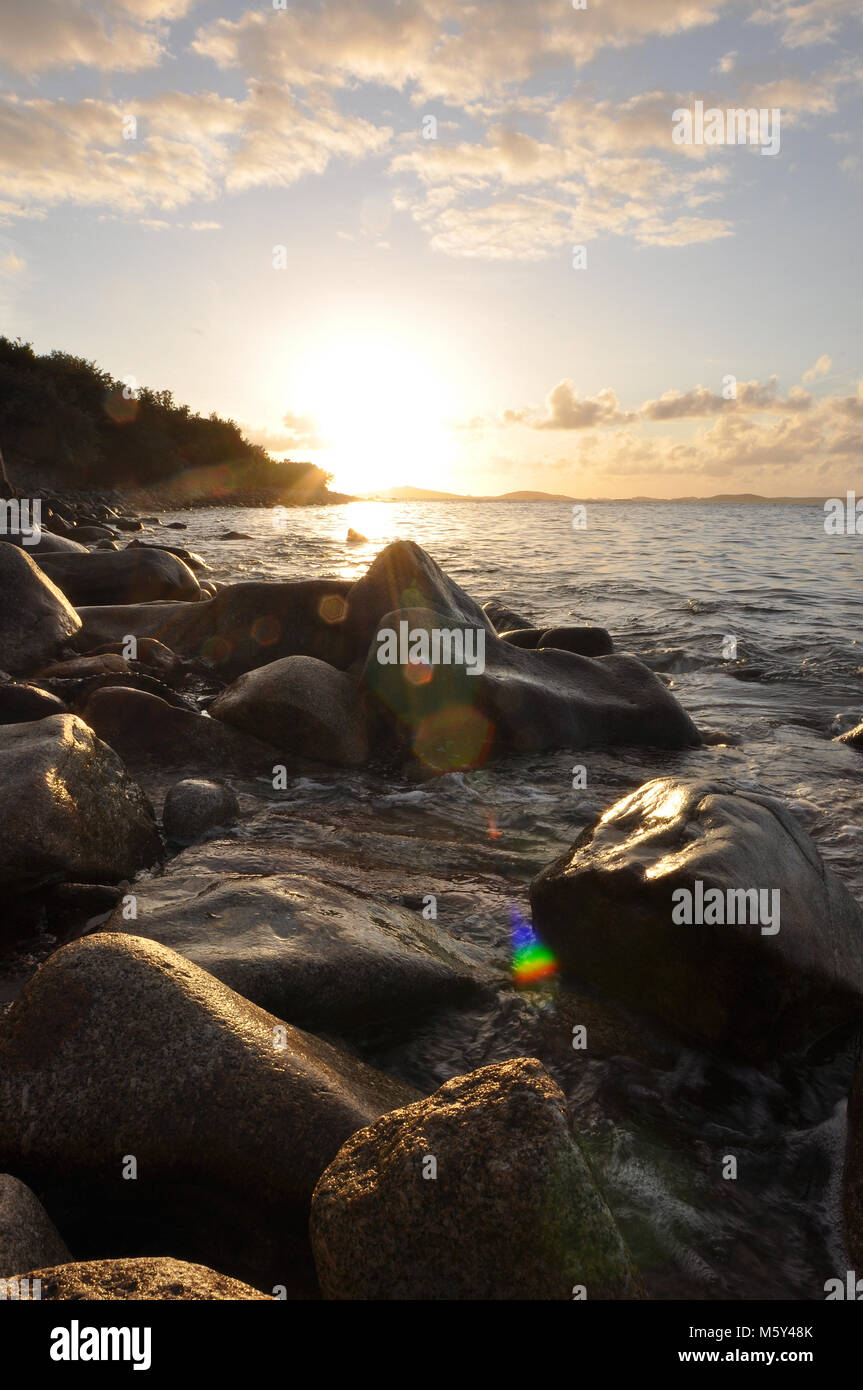 Sunset seascape across rocky coastline. Isles of Scilly, views across the sea to Samson island at sunset. Stock Photo