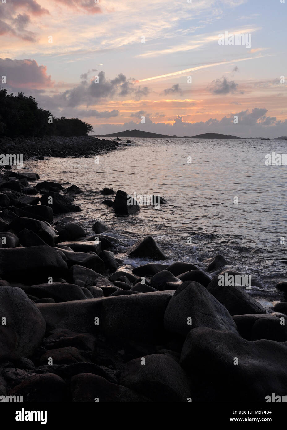 Sunset seascape across rocky coastline. Isles of Scilly, views across the sea to Samson island at sunset. Stock Photo