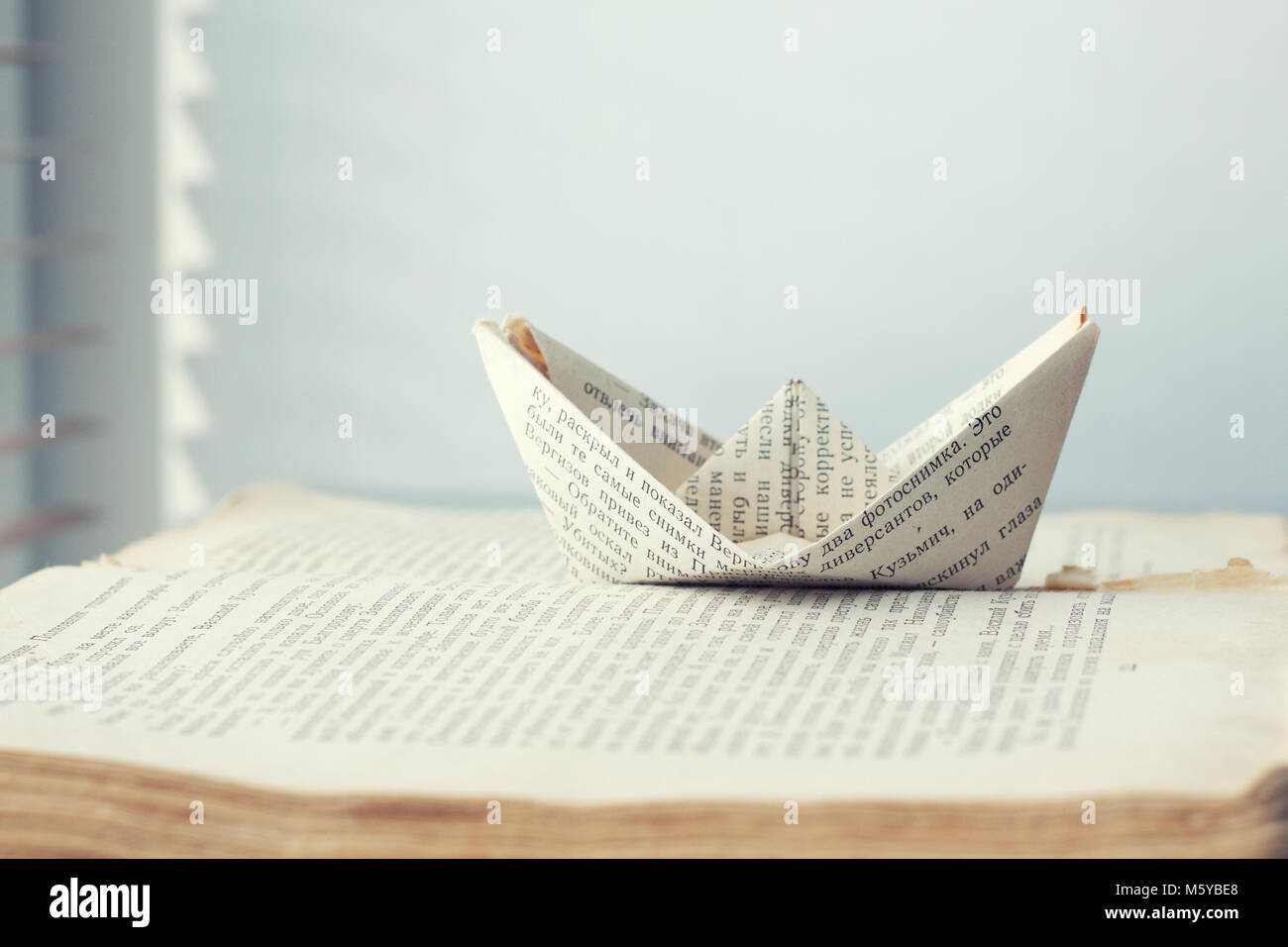 a paper ship is sent to the path of knowledge and words on sea book background editorial Stock Photo