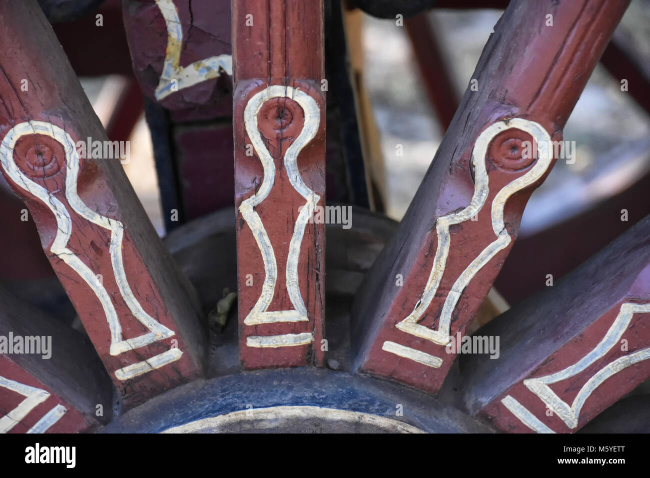 Close up of a red colored hand painted ox wagon wheel with white lines from South Africa Stock Photo