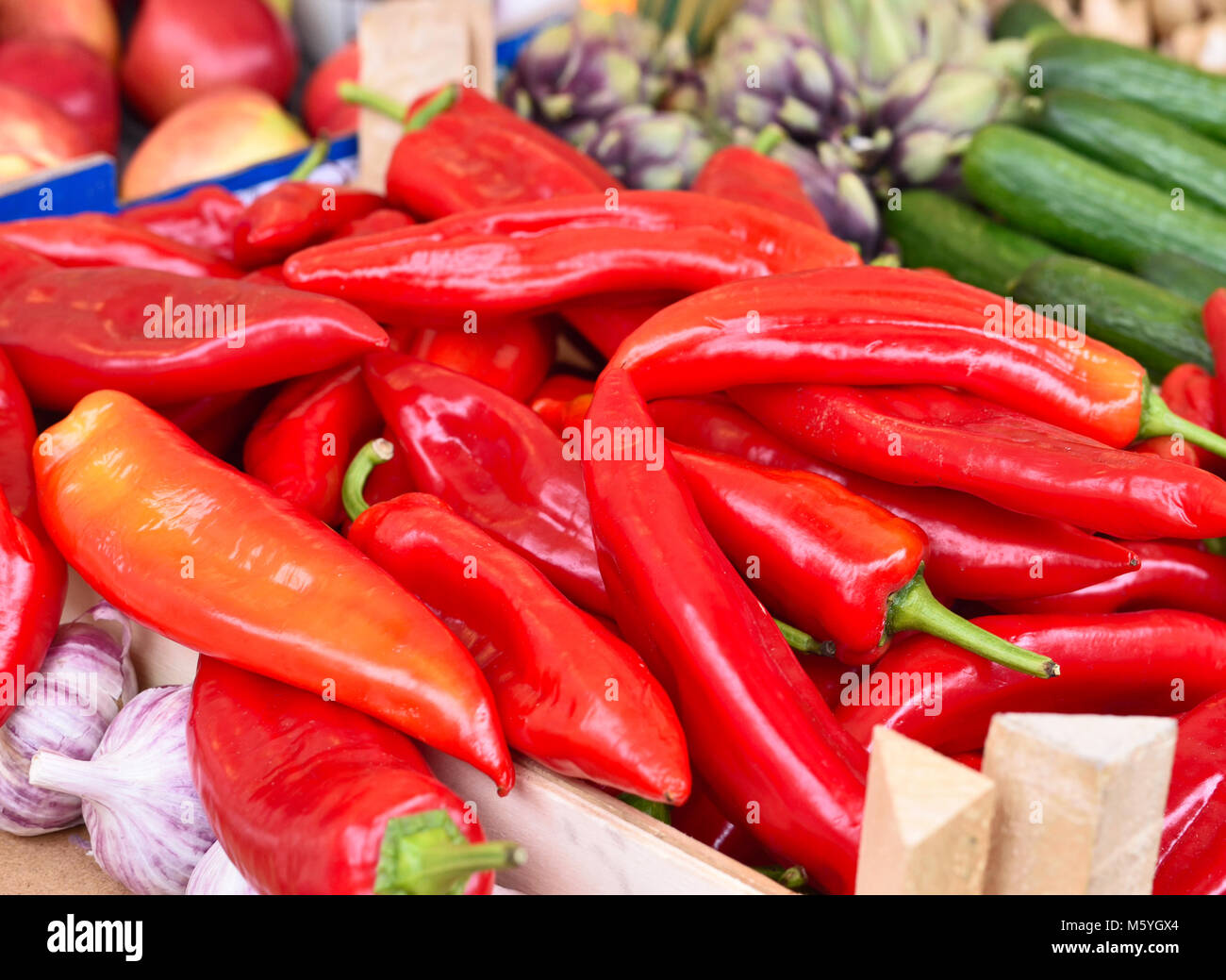 Fresh vegetables on a farmers market stall, closeup shot with selective focus. red bell pepper, garlic, cucumber and apples on market. Stock Photo