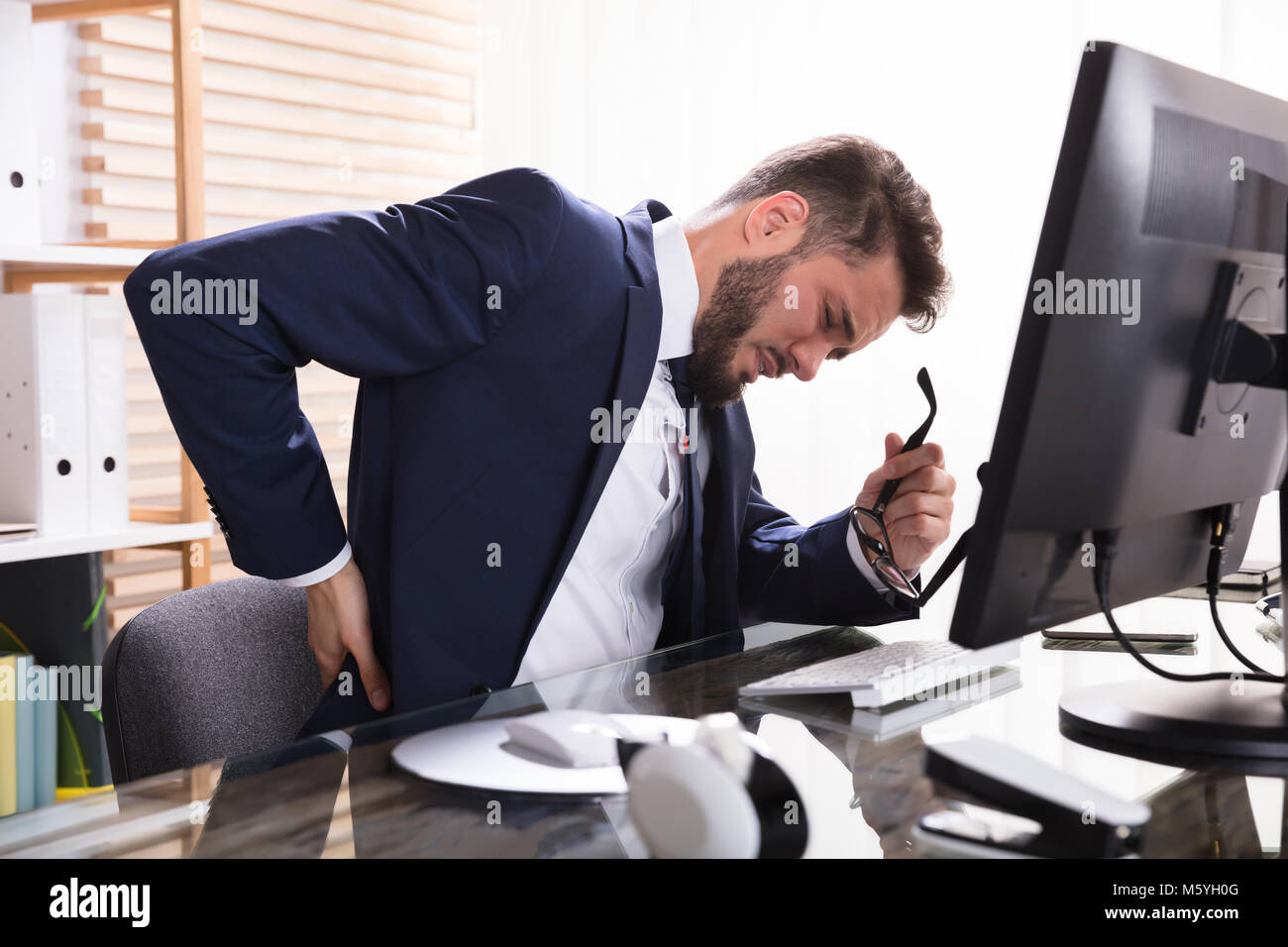 Young Businessman Suffering From Backache At Workplace Stock Photo