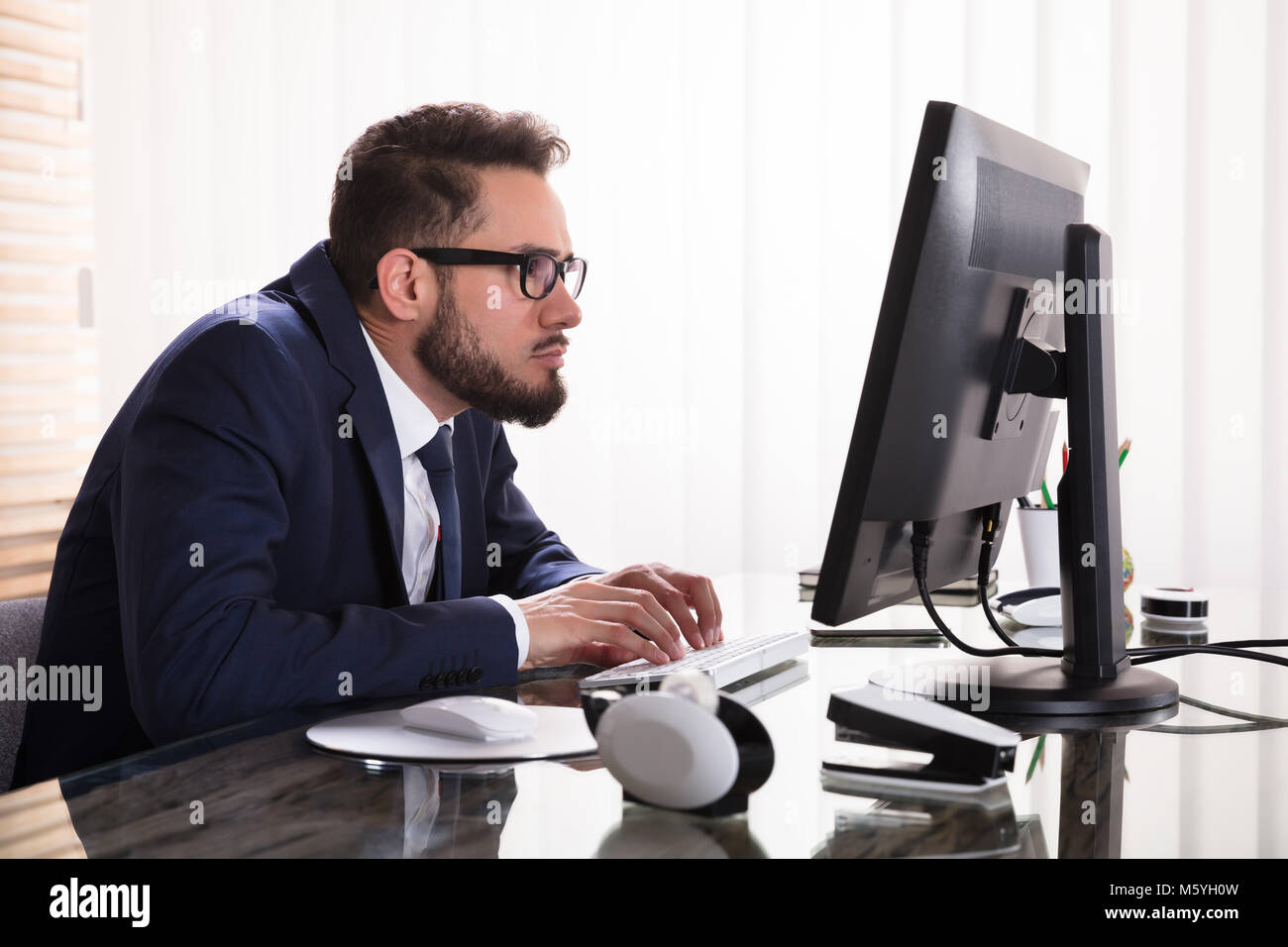 Man Sitting In Bad Posture Working On Computer In Office Stock