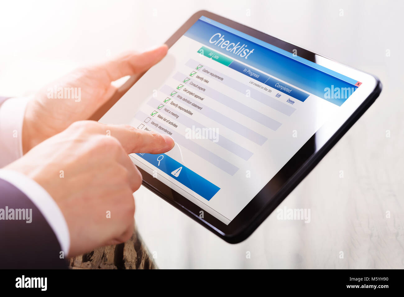Close-up Of A Businessperson's Hand Filling Checklist Form On Digital Tablet Stock Photo