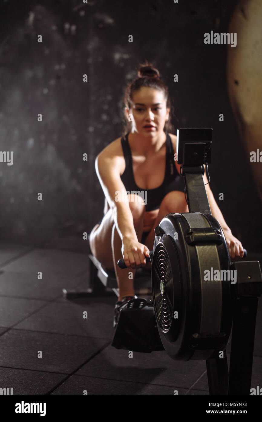 female using rowing machine in gym. woman doing cardio workout in fitness club. Stock Photo