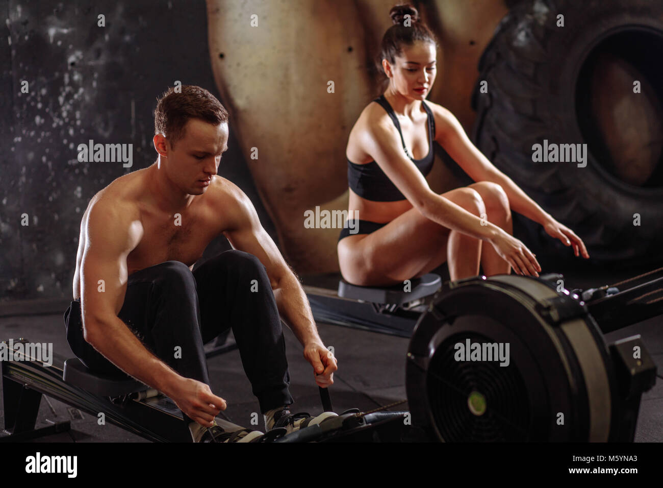 couple doing exercises with rowing machine Stock Photo