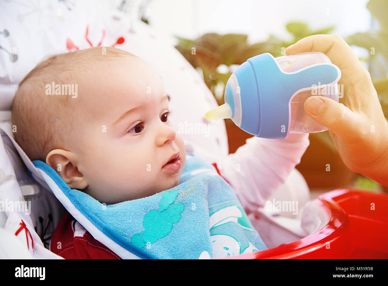 Adorable Curious baby drinks water from the bottle. Happy and emotional