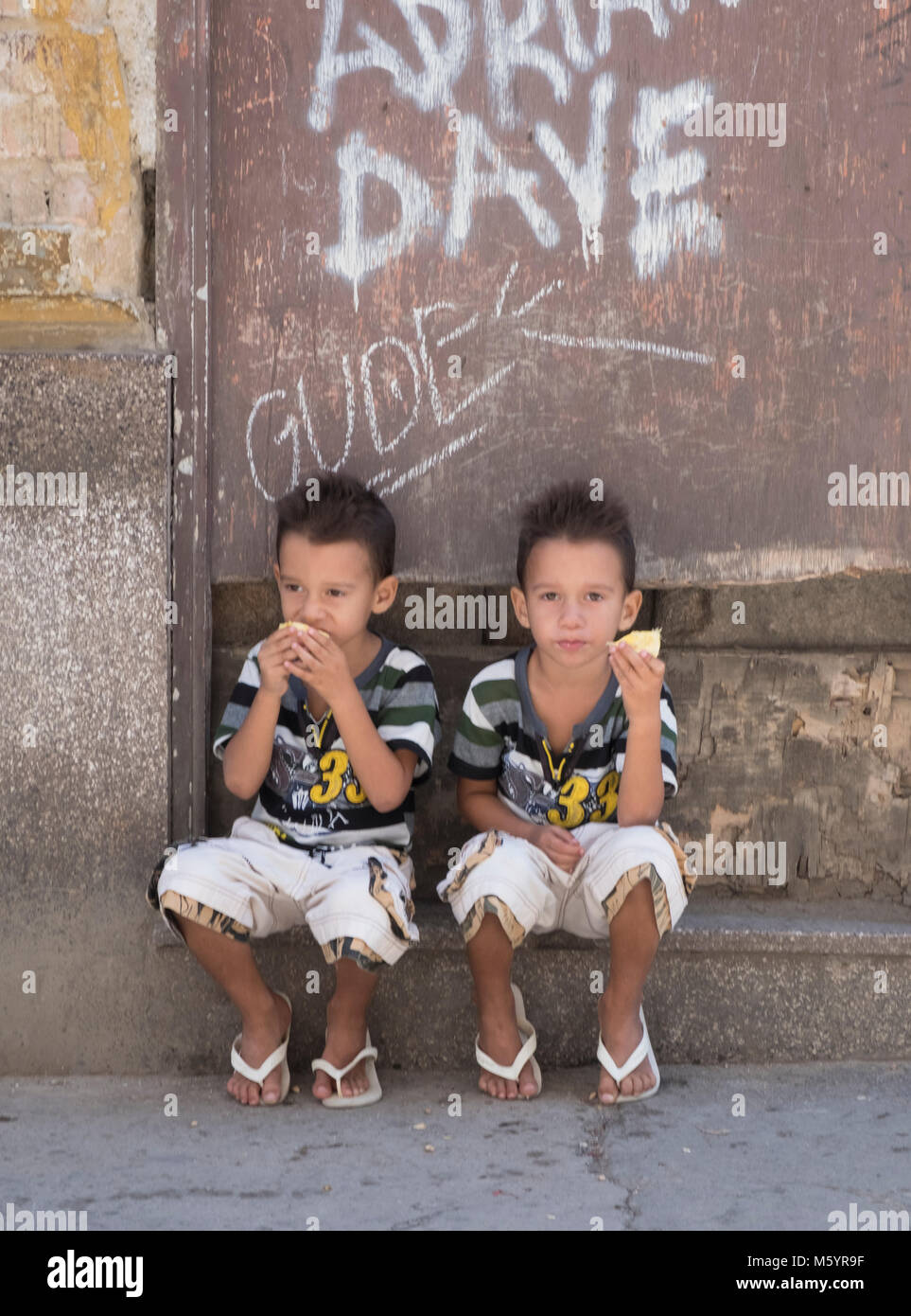 Young twins eating fruit in Havana, Cuba Stock Photo