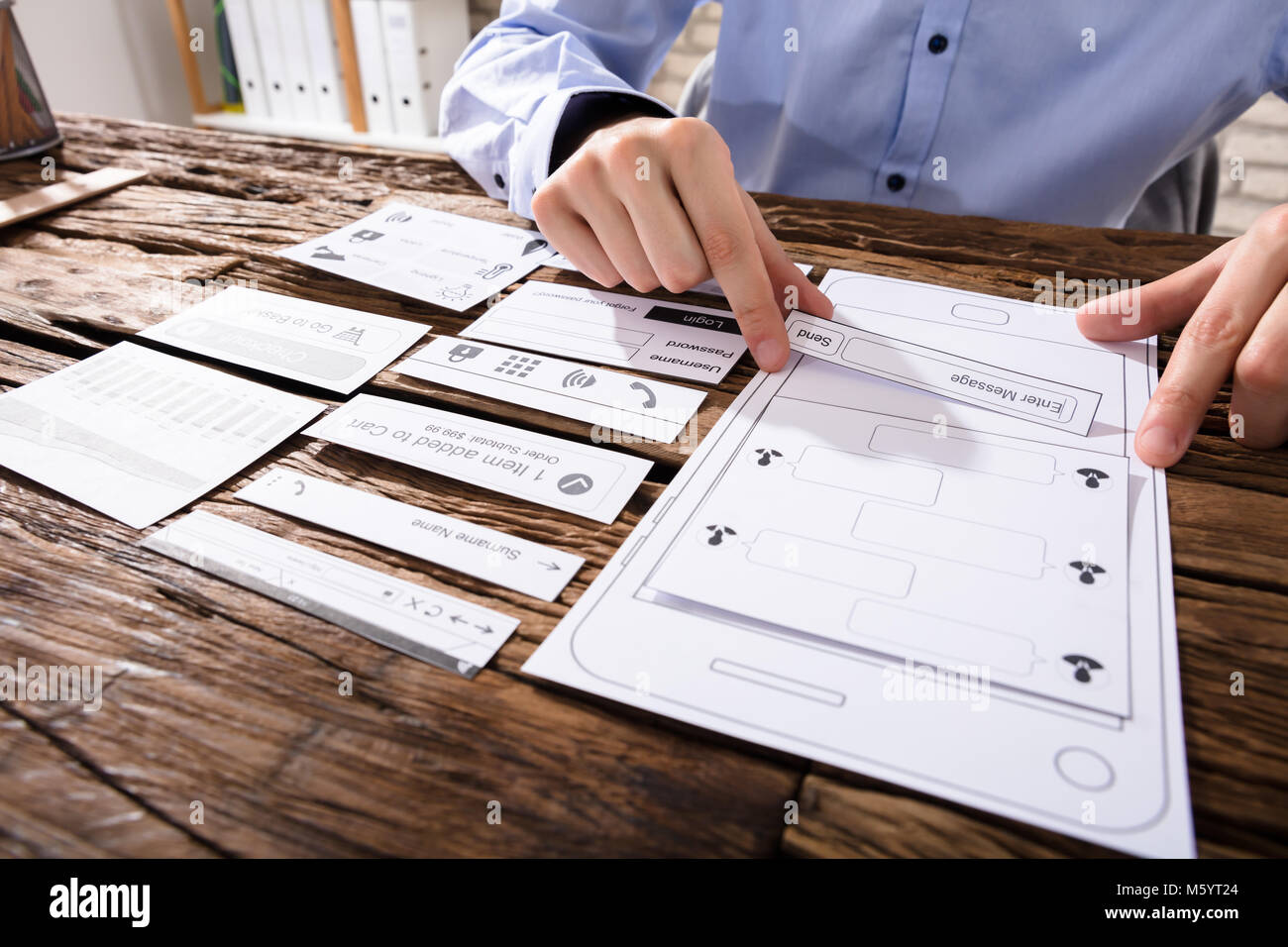 Close-up Of A Designer's Hand Designing Mobile Application Over Wooden Desk Stock Photo