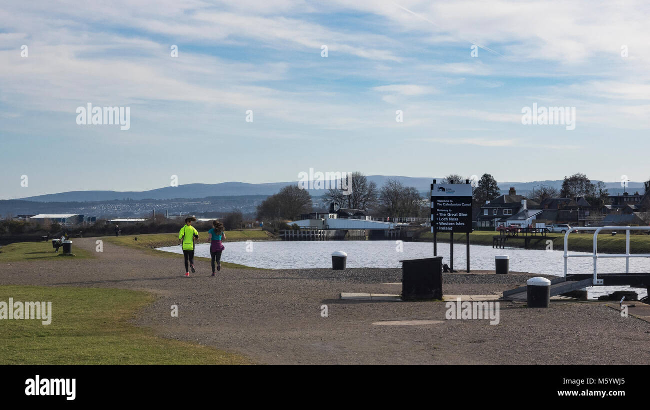 Two females running by the Clachnaharry Sea Loch where the Caledonian Canal meets the Beauly Firth, Inverness, Scotland Stock Photo
