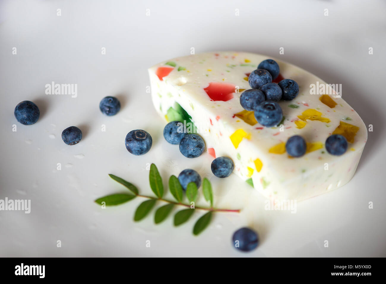 Dessert - Cheesecake  with colorful jelly and blackberries on white background Stock Photo