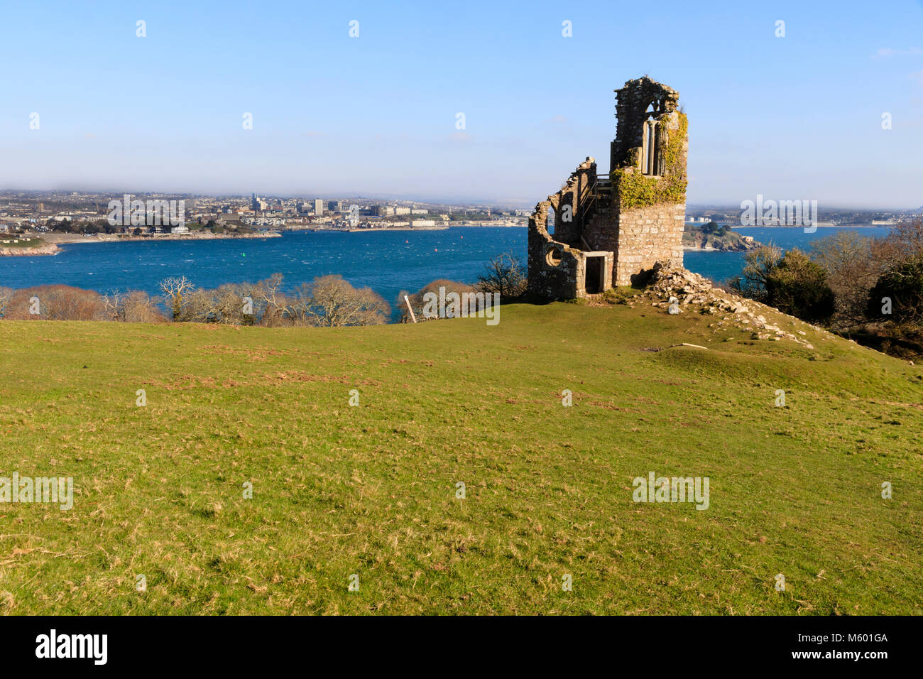 Winter sunlight illuminates a view from the folly at Mountt Edgcumbe, Cornwall, across Plymouth Sound to the Plymouth waterfront Stock Photo