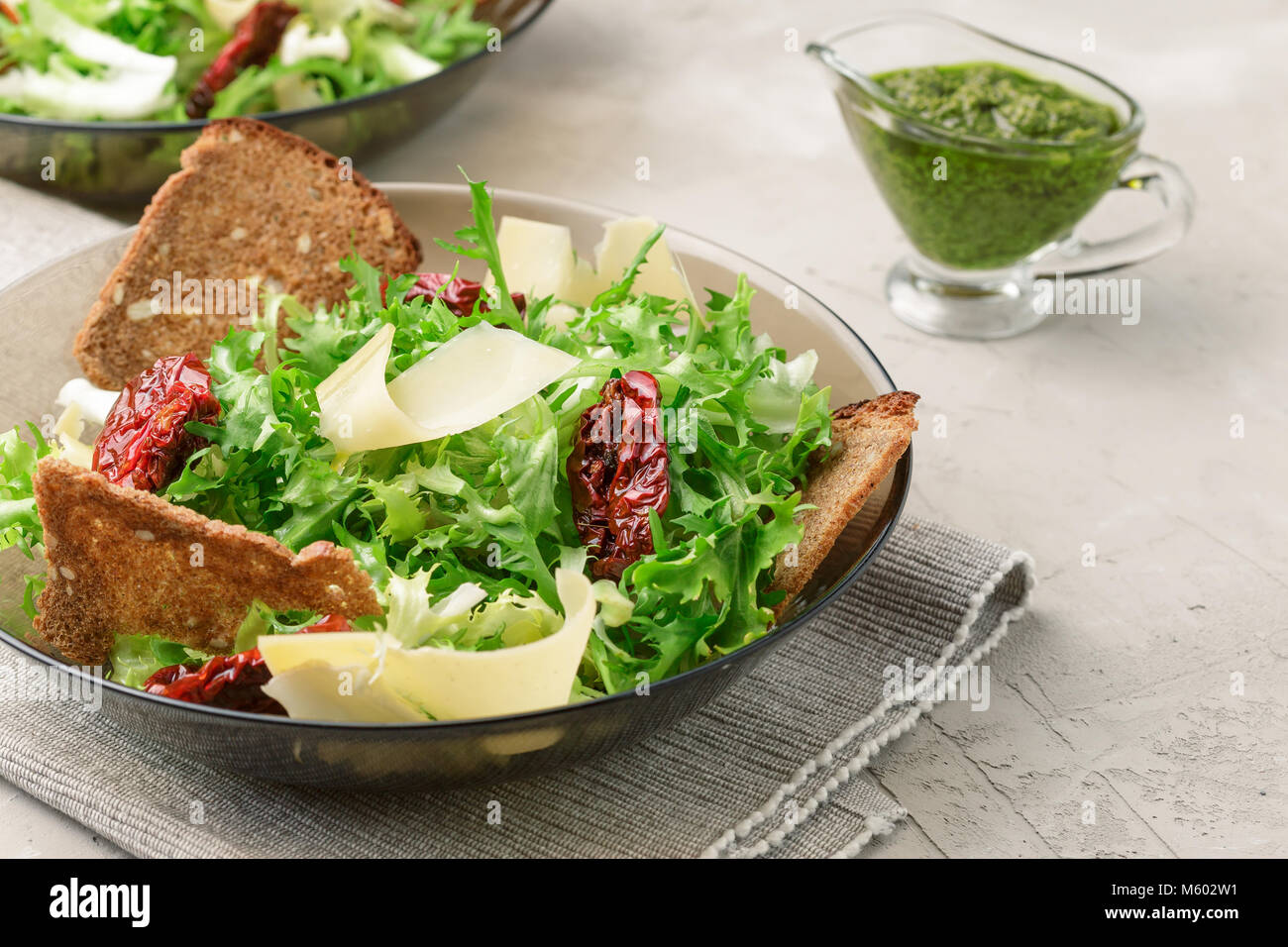 Salad with frisee lettuce, sun dried tomatoes, cheese, bread chips and