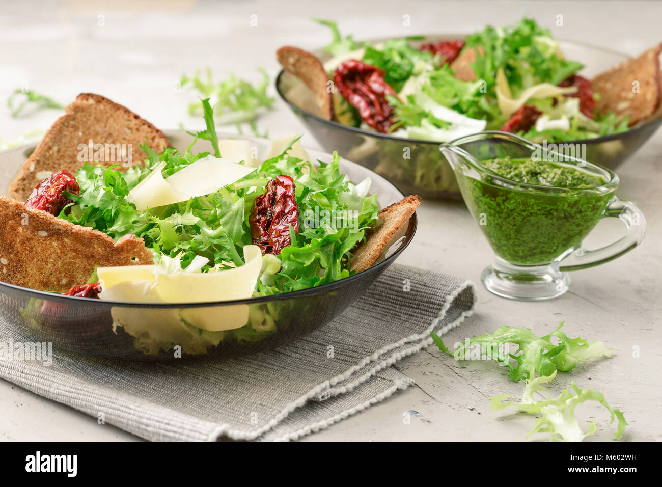 Salad with frisee lettuce, sun dried tomatoes, cheese, bread chips and