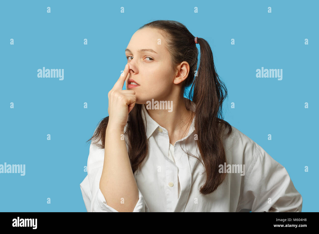 fun girl on blue background show pig snout gesture Stock Photo