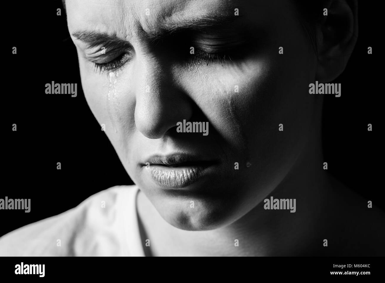 sad woman crying on black background, closeup portrait, monochrome Stock Photo