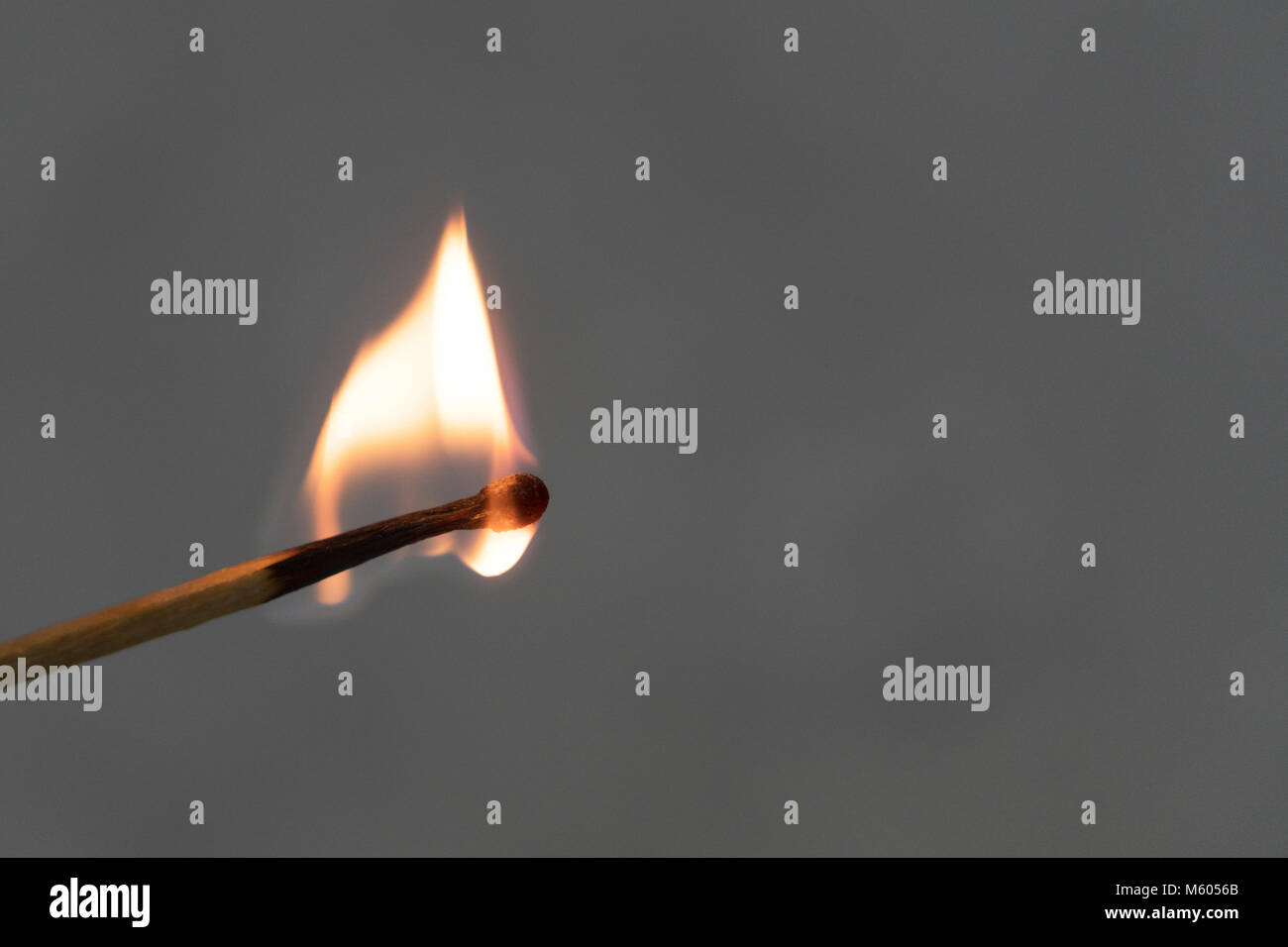 A lit match against a gray background. Fire burns. Stock Photo