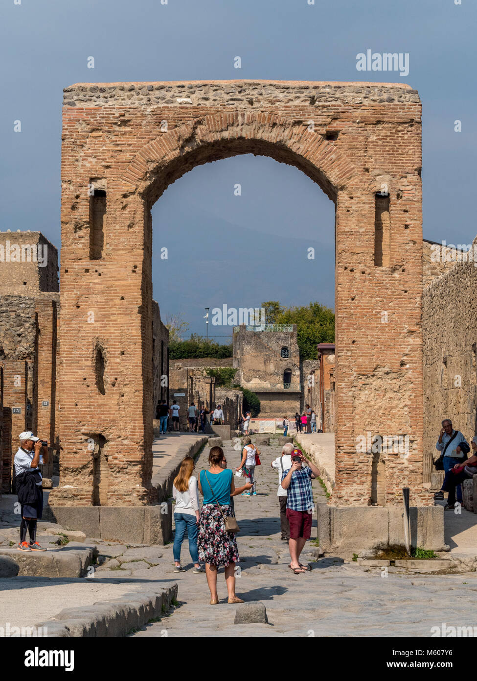 Tourists photographing the Honorary arch in Pompeii ruins, Italy. Stock Photo
