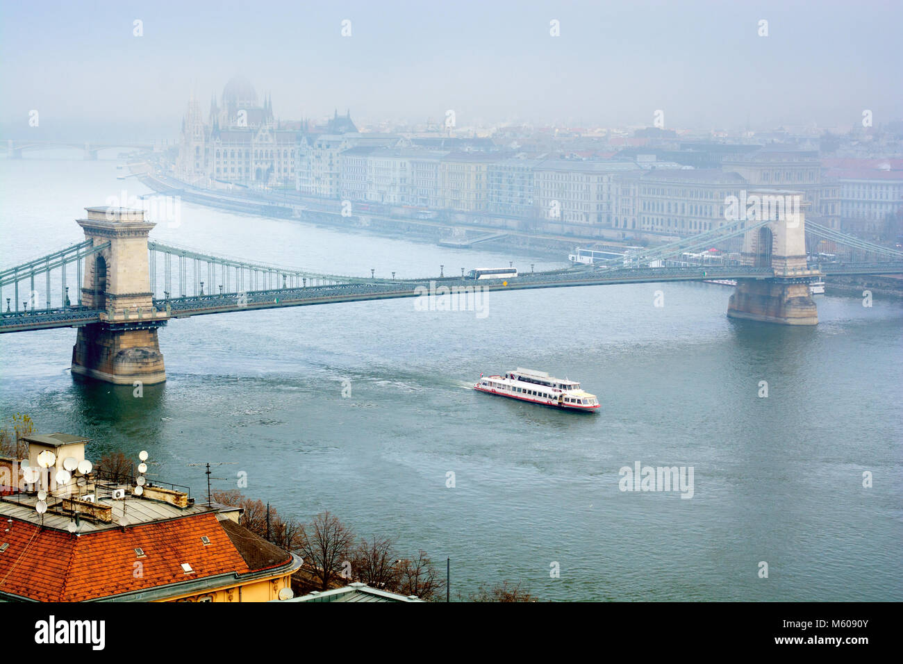 Danube river in fog, sightseeing boat passing under Chain Bridge, Budapest Stock Photo