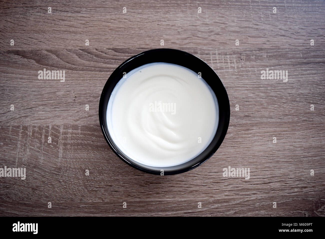 Ceramic bowl of white yogurt isolated on wooden background from above