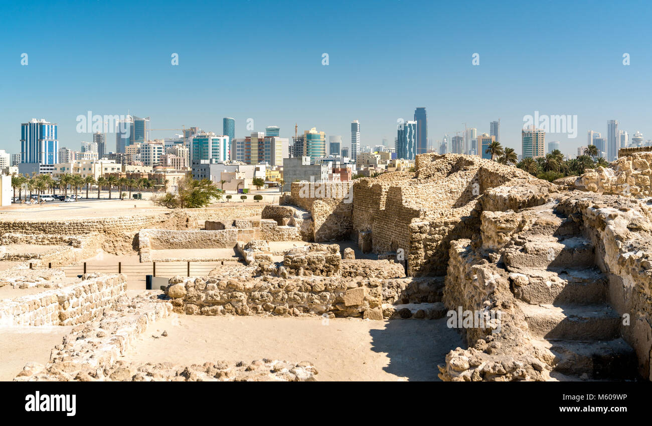 Ruins of Bahrain Fort with skyline of Manama. A UNESCO World Heritage Site Stock Photo