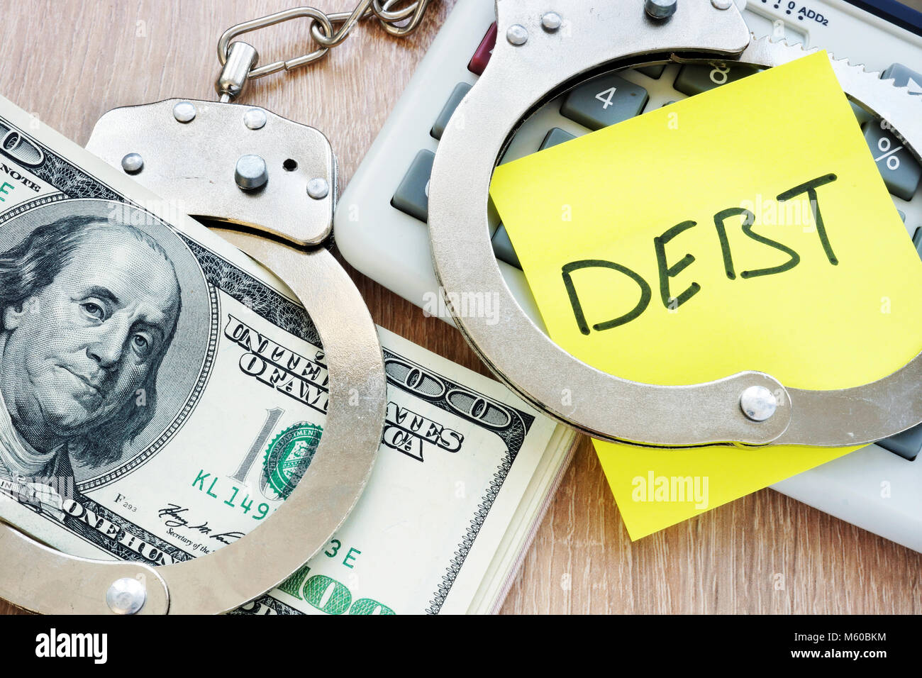 Debt in handcuffs and money for payment. Problems with loans. Stock Photo