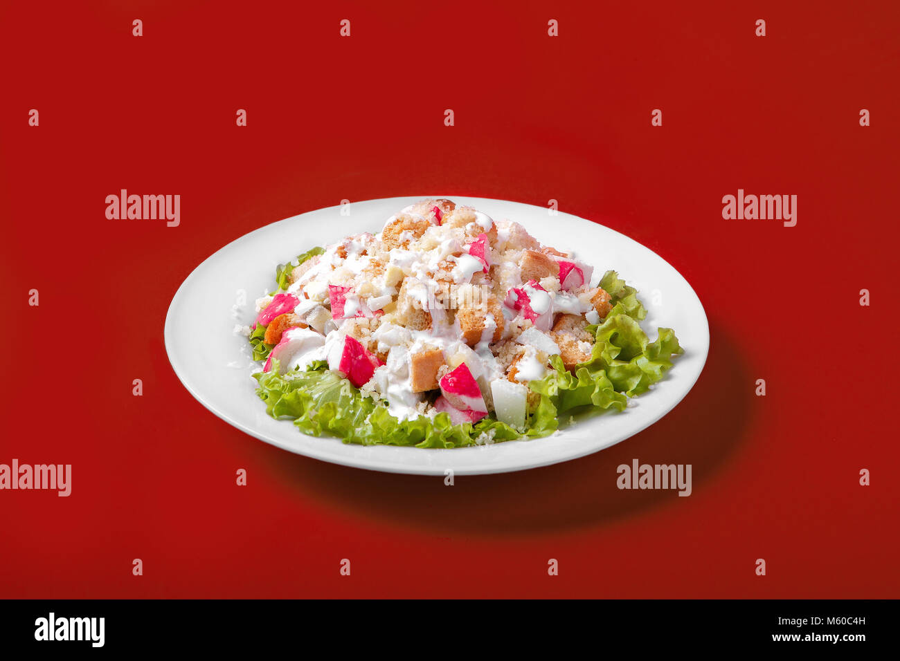 Salad with crab meat, breadcrumbs on a monophonic red background. It is