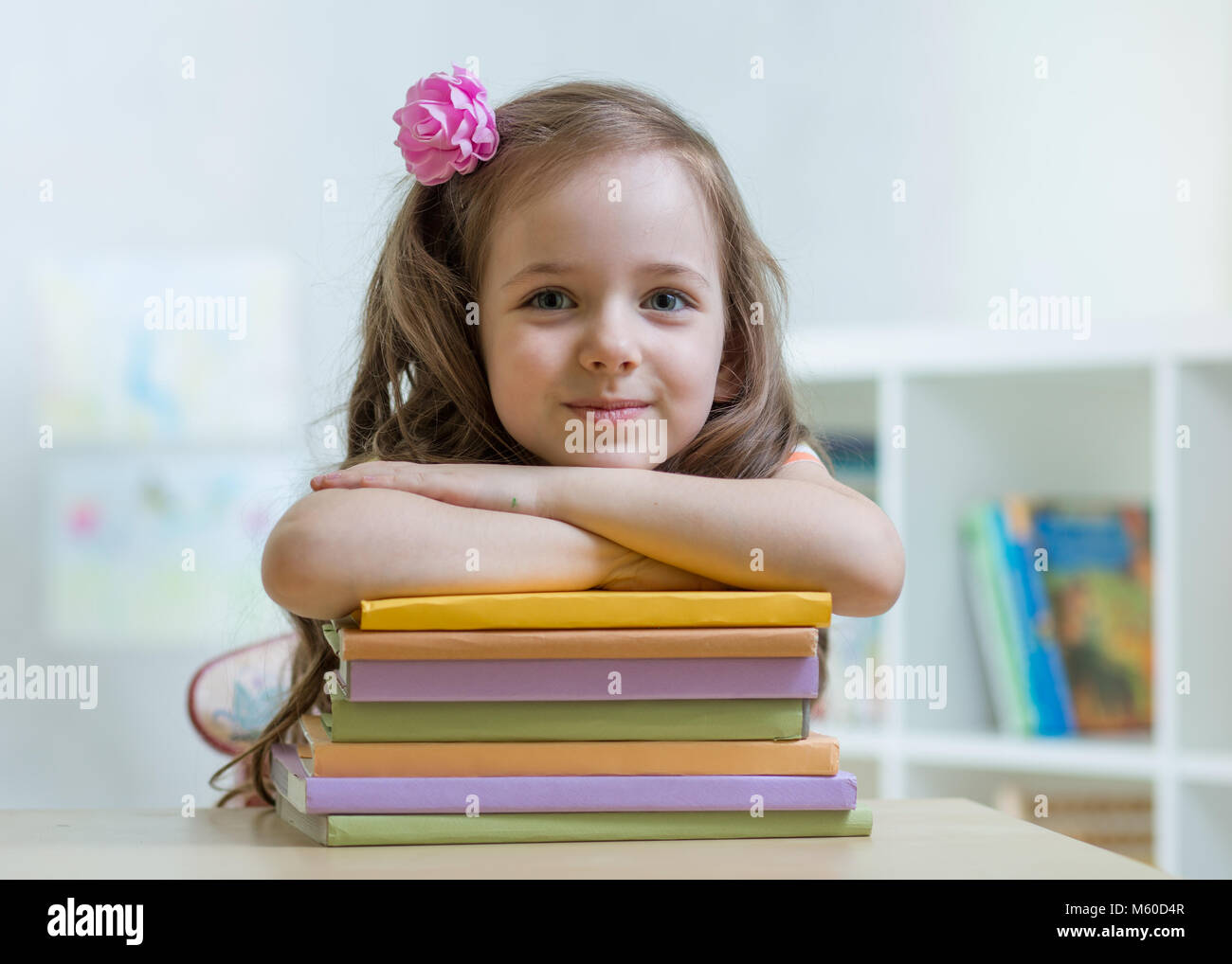 Happy kid girl with a stack of books at home Stock Photo - Alamy